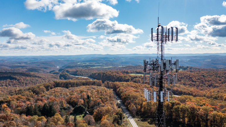 Aerial view of mobile phone cell tower over forested rural area of West Virginia to illustrate lack of broadband fiber internet service