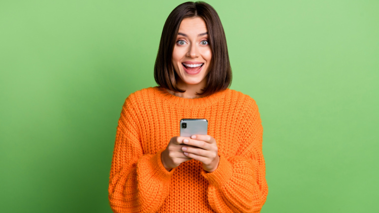Portrait of attractive cheerful amazed girl using gadget social network post isolated over bright green color background, week #26