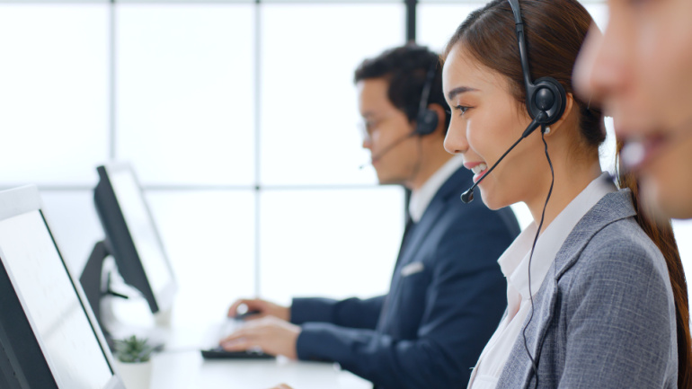 Asian call center team, asian telecom, customer service, telesales in formal suit wearing headset or headphone talking with customer in modern office