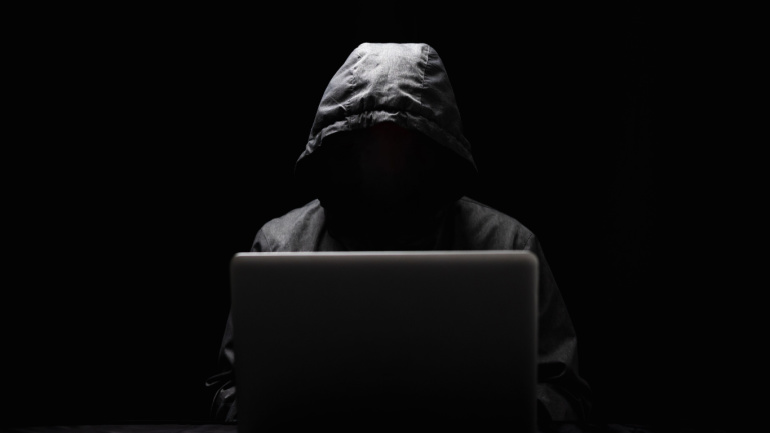 Hackers wear hoods to cover their faces. Hacking to steal important information. Use a computer to release malware viruses Ransom and harass organizations. He sitting in the dark room with neon light. Ransomware attack.