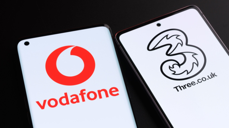 Vodafone and Three potential merger concept. Two smartphones seen together with UK mobile operator logos on the screens. Stafford, United Kingdom, October 3, 2022.