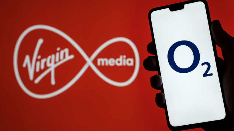 O2 Telefonica logo on smartphone screen hold in hand and Virgin Media O2 logo on blurred background. Concept for Virgin and O2 merger.